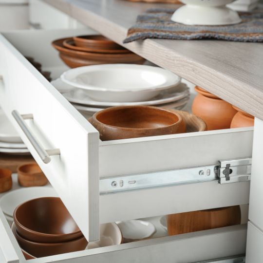 Open kitchen drawers containing plates and bowls